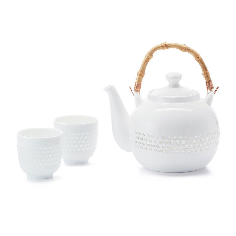 White porcelain teapot with bamboo handle and two matching cups on a white background