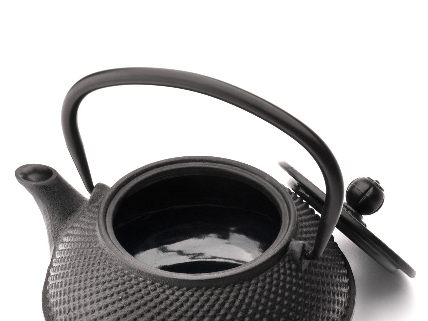 Black textured cast iron teapot on a white background