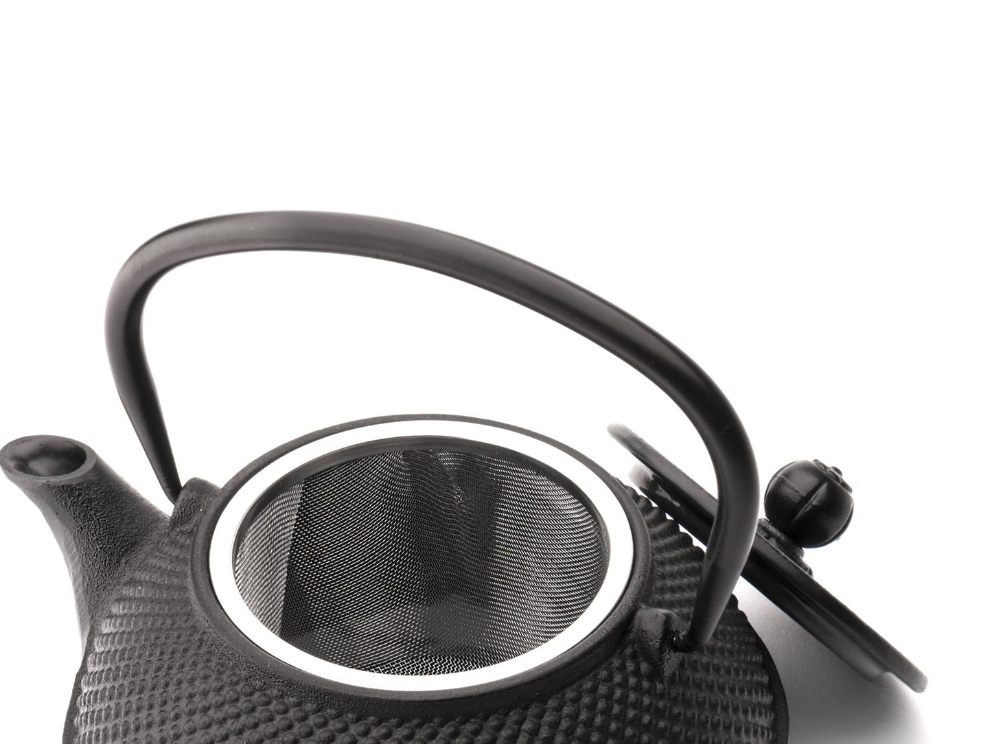 Black textured cast iron teapot with a mesh filter on a white background