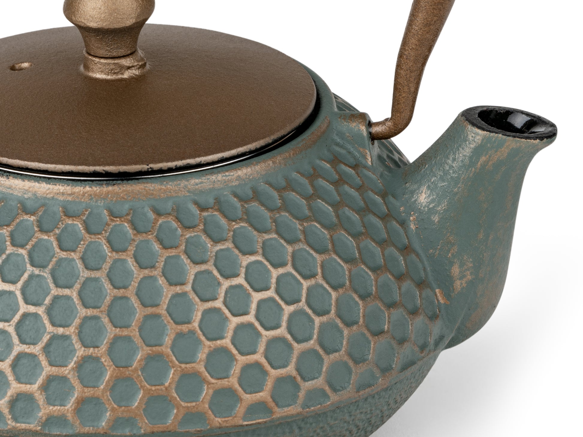 Detail of dark teal blue teapot with honeycomb textured surface and dark matt gold lid on a white background