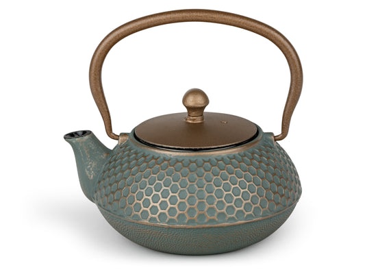 Teapot in dark teal with honeycomb design textured and distressed surface and dark matt gold lid and handle on a white background