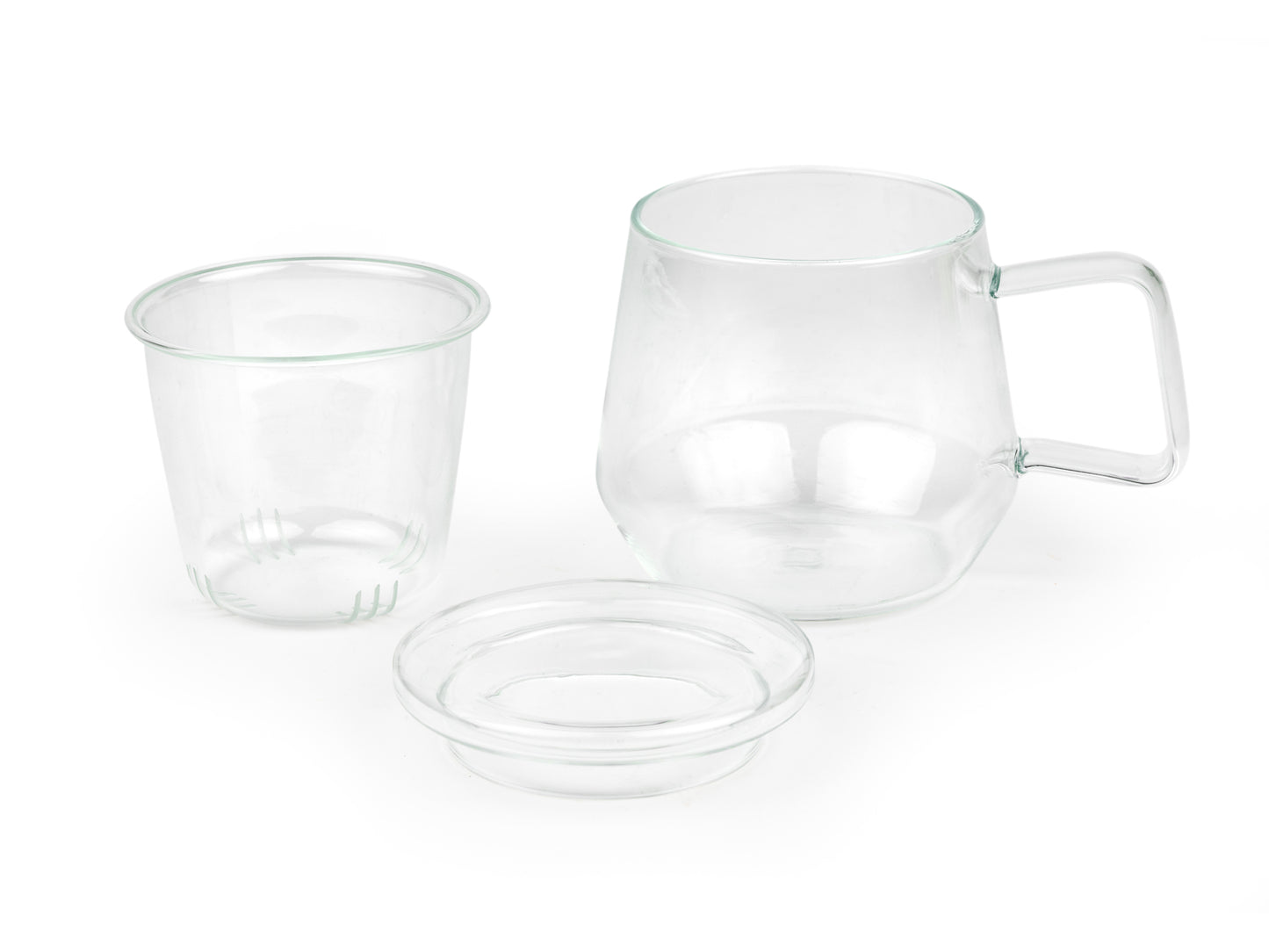 3 piece clear glass mug with handle sitting next to its removed glass infuser and lid on a white background