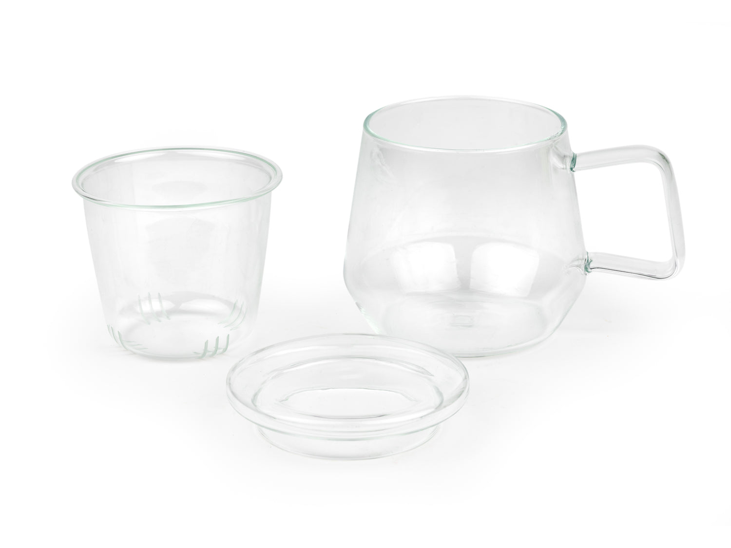 3 piece clear glass mug with handle sitting next to its removed glass infuser and lid on a white background