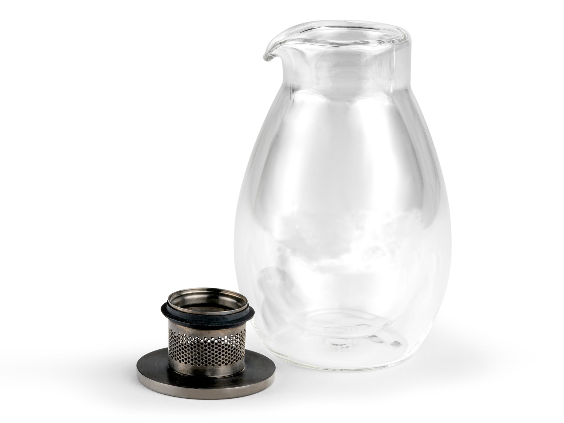 Clear glass handle-less teapot with metal lid and filter removed on a white background