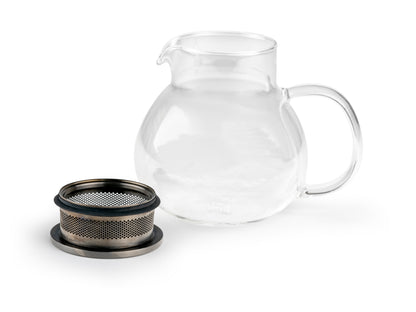Clear glass teapot with metal filter in the lid which has been removed on a white background