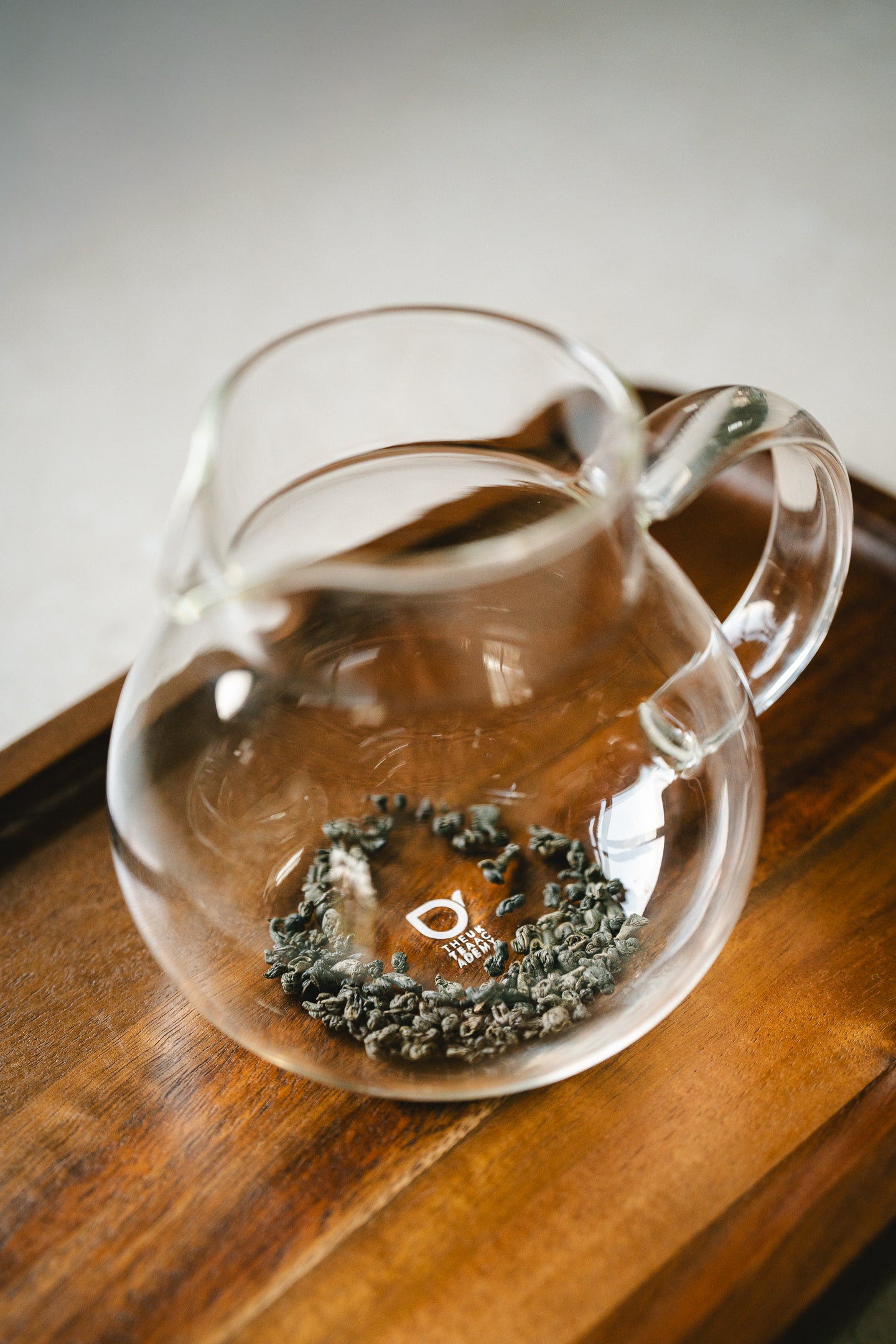 Clear glass teapot filled with balled tea on a wooden surface