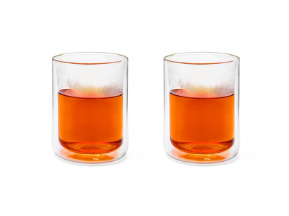 Two clear glass tumblers filled with hot tea on a white background