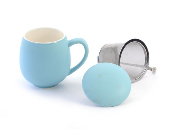 Light blue porcelain mug with a matching lid and metal tea filter on a white background
