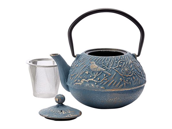 Blue and gold cast iron teapot with its lid and infuser basket removed on a white background