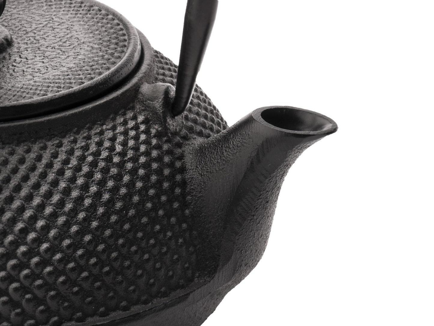 Close up detail of black textured cast iron teapot on a white background