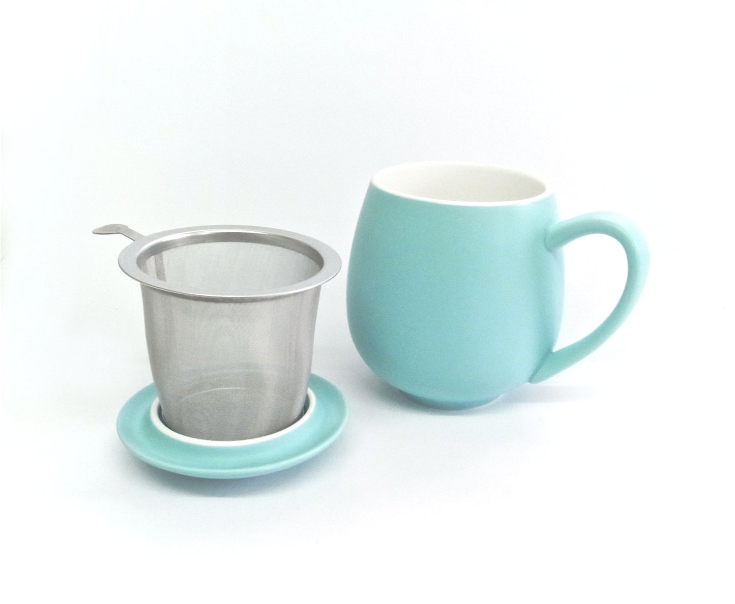 Teal porcelain tea mug with metal tea infuser sitting on a lid on a white background