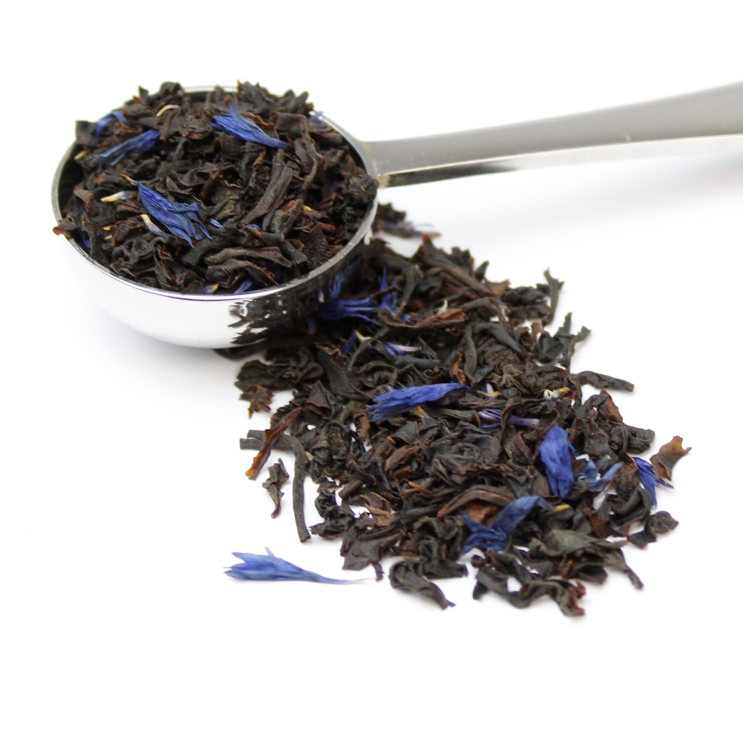 Loose leaf decaf earl grey black tea with blue cornflower petals in a silver teaspoon on a white backround.