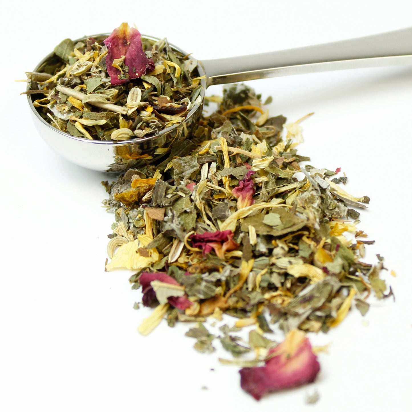 Herbal tea blend in silver teaspoon on a white background.