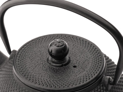 Close-up of a black cast iron teapot lid with textured surface