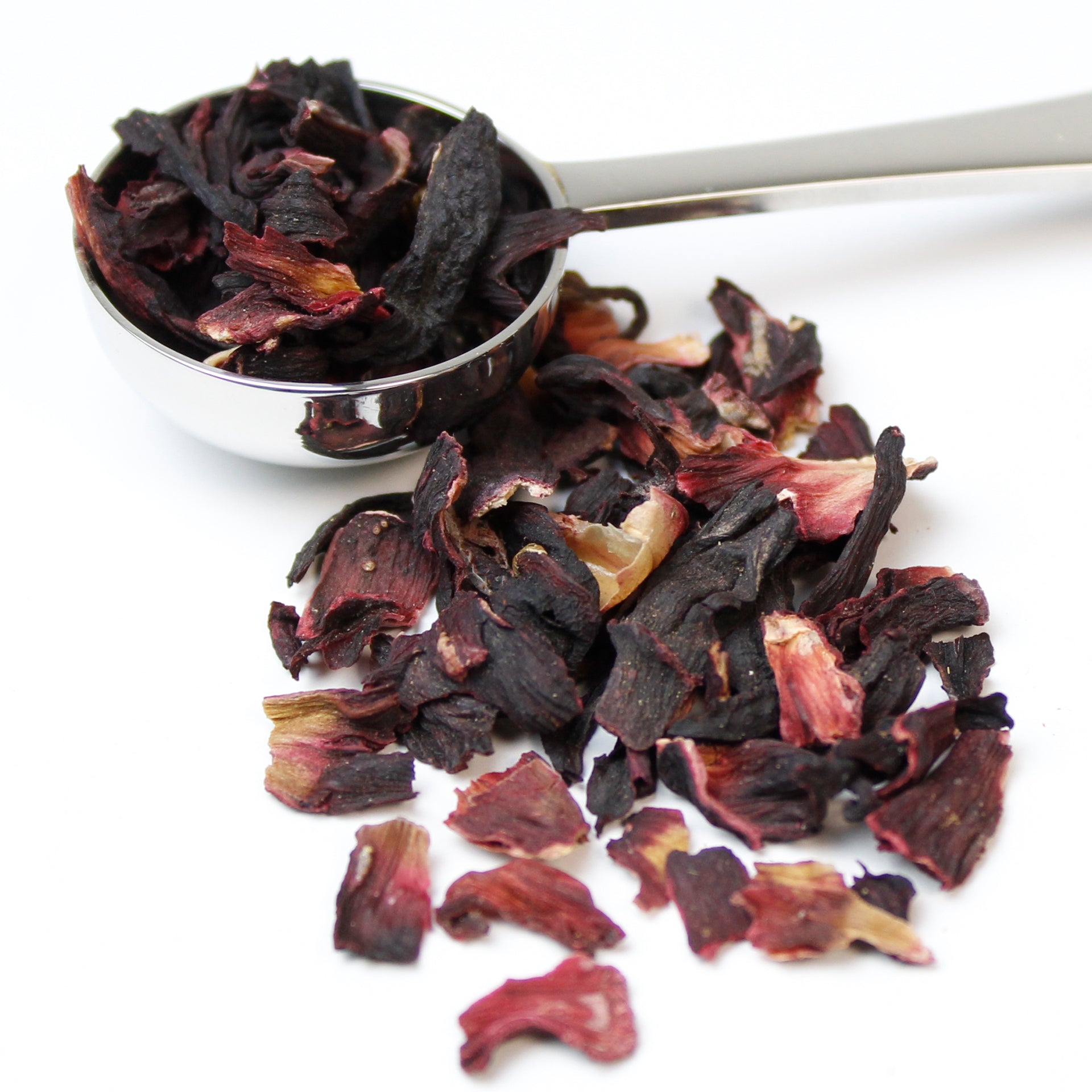 Loose leaf hibiscus blossom in a silver teaspoon on a white background