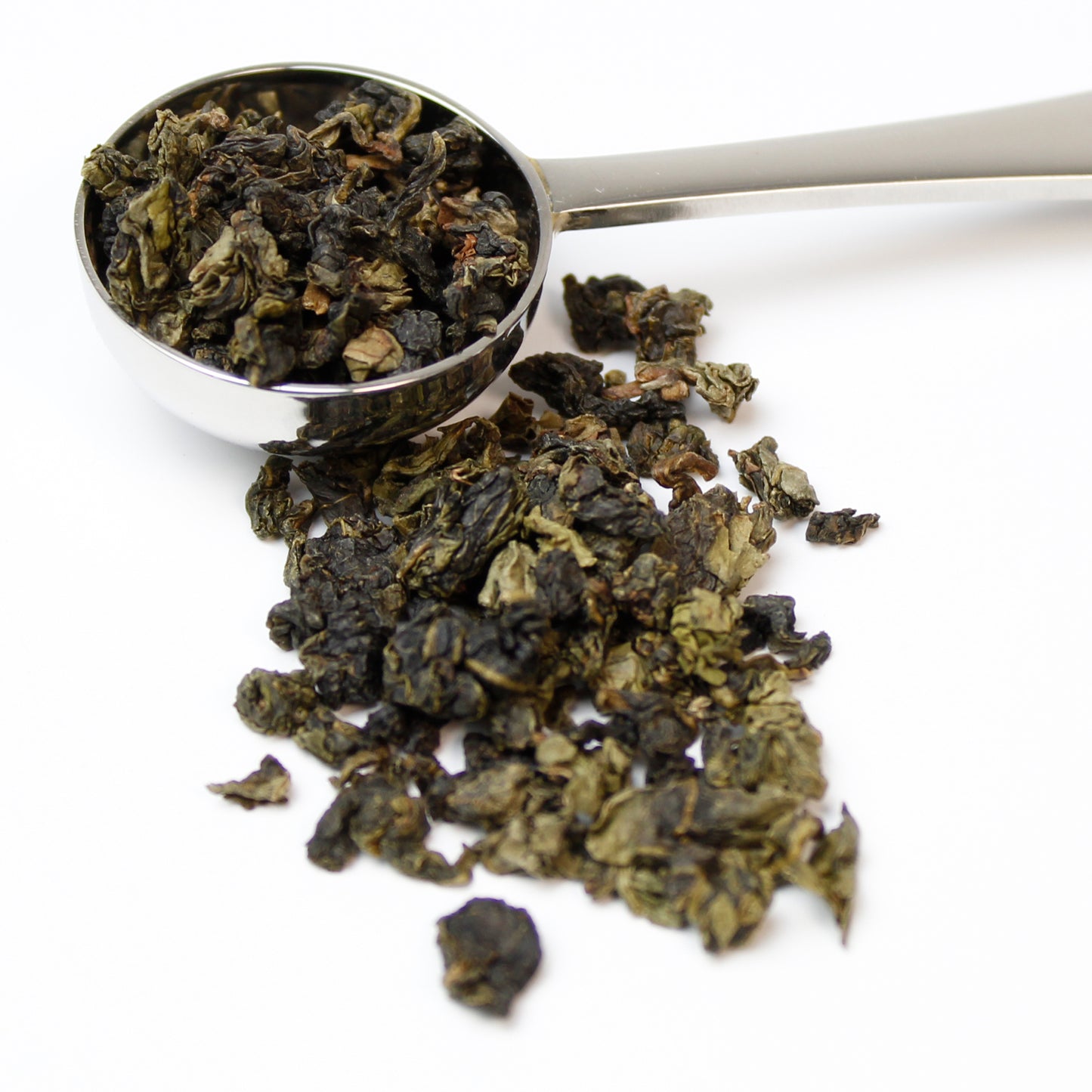 Silver teaspoon filled with Phoenix Oolong tea spilling over on to a white background