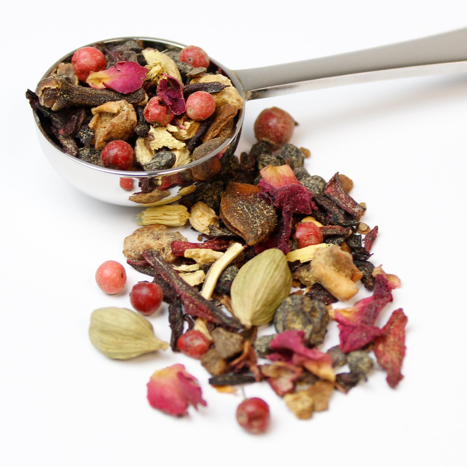 Loose blend of fruit, spices and rose petals in a silver teaspoon on a white background