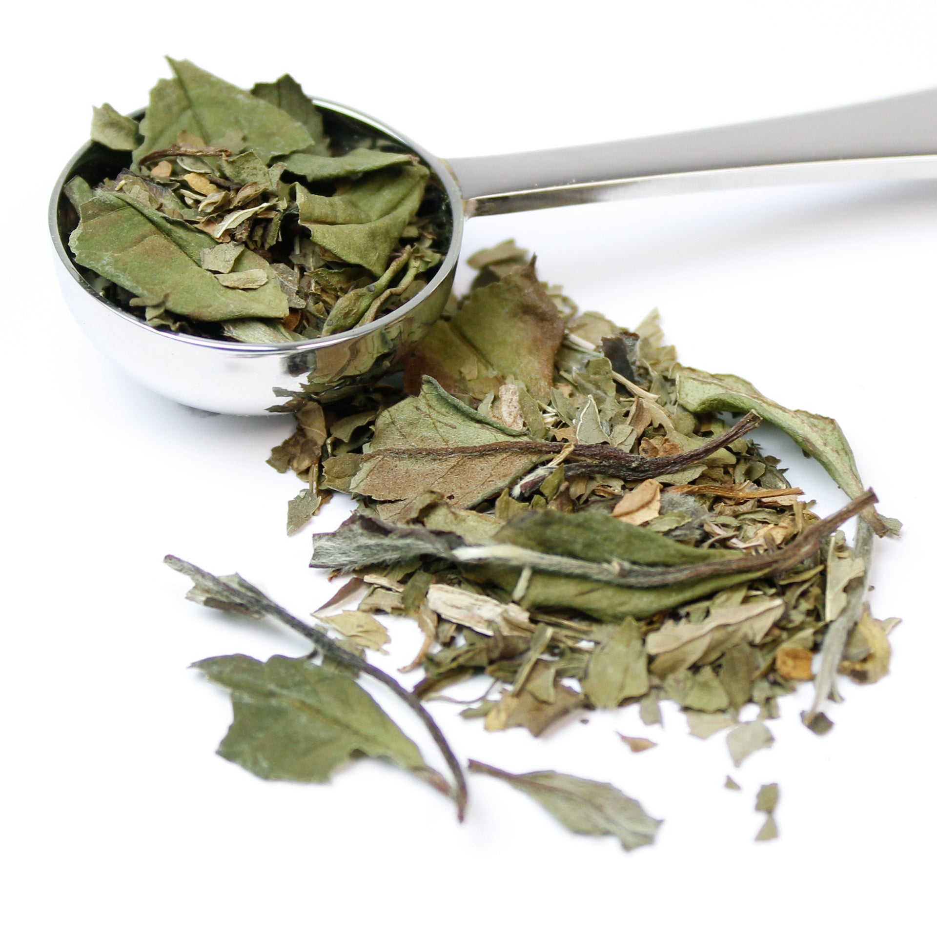 Silver teaspoon full of 'Morning Dew' loose tea leaves spilling onto a white background